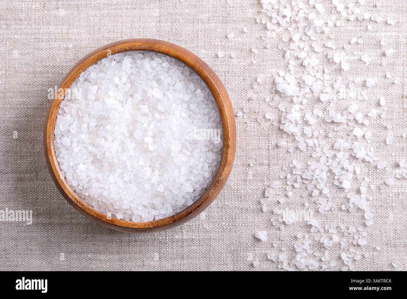 Grobes Salz aus dem Toten Meer in einer Holzschale auf Leinen. Kristallisiertes Salz aus dem Toten Meer. Stockfoto