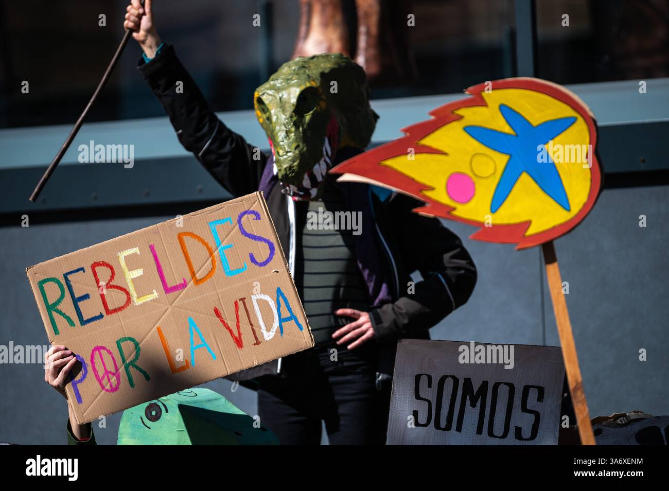 Madrid, Spanien. März 2025. Klimaaktivist der Extinction Rebellion Gruppe mit Dinosauriermaske, die vor der Ausstellung Patagonischer Dinosaurier auf dem CaixaForum protestiert, um anzuprangern, dass die CaixaBank Gruppe ihre Investitionen in die fossile Brennstoffindustrie weiter erhöht. Der Protest findet zeitgleich mit dem Weltklimatag statt. Quelle: Marcos del Mazo/Alamy Live News Stockfoto