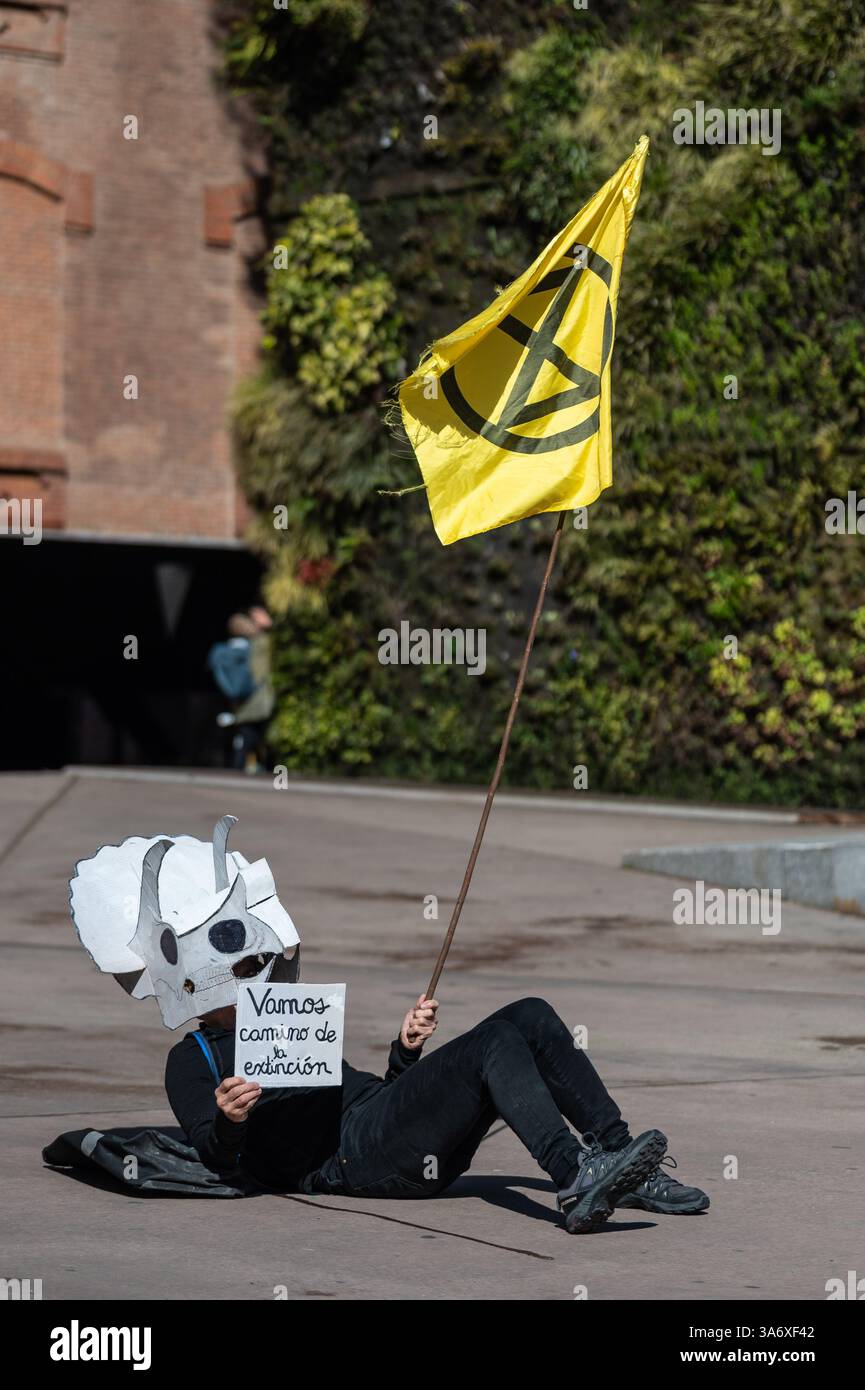 Madrid, Spanien. März 2025. Klimaaktivist der Extinction Rebellion Gruppe mit Dinosauriermaske, die vor der Ausstellung Patagonischer Dinosaurier auf dem CaixaForum protestiert, um anzuprangern, dass die CaixaBank Gruppe ihre Investitionen in die fossile Brennstoffindustrie weiter erhöht. Der Protest findet zeitgleich mit dem Weltklimatag statt. Quelle: Marcos del Mazo/Alamy Live News Stockfoto