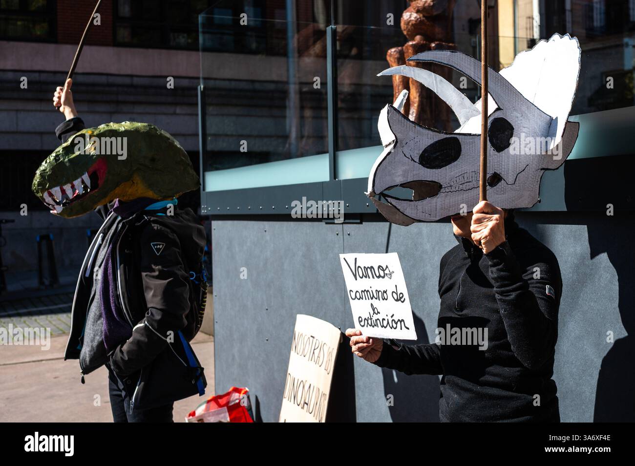 Madrid, Spanien. März 2025. Klimaaktivisten der Gruppe Extinction Rebellion, die Dinosauriermasken tragen, protestieren vor der Ausstellung Patagonischer Dinosaurier auf dem CaixaForum, um anzuprangern, dass die CaixaBank-Gruppe ihre Investitionen in die fossile Brennstoffindustrie weiter erhöht. Der Protest findet zeitgleich mit dem Weltklimatag statt. Quelle: Marcos del Mazo/Alamy Live News Stockfoto