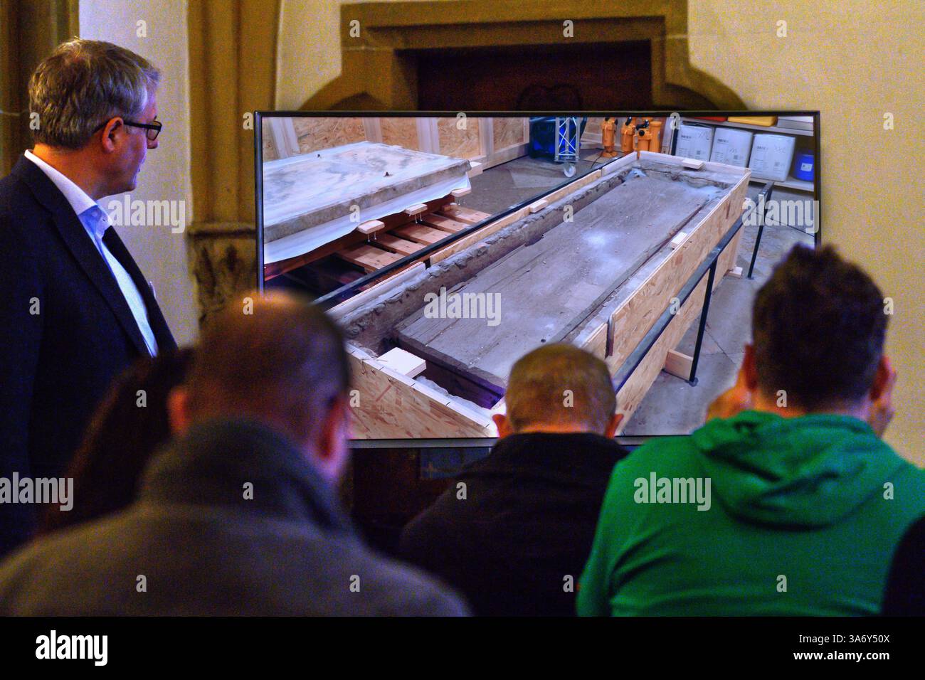 26. März 2025, Sachsen-Anhalt, Magdeburg: In der Sakristei des Magdeburger Doms erklärt Donat Wehner (l) vom Landesamt für Denkmalpflege und Archäologie Sachsen-Anhalt Medienvertretern die Beschädigung der Holzkiste im offenen Sarkophag mit Hilfe einer Live-Videoübertragung aus dem Gehege rund um das Grab Ottos des Großen. Seit Januar führen das Landesamt für Denkmalpflege und Archäologie und die Kulturstiftung Sachsen-Anhalt Untersuchungen zur Erhaltung des Denkmals durch. Bisherige Ergebnisse und weitere geplante Ergebnisse Stockfoto