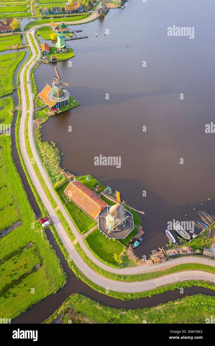 Luftaufnahme der typischen Windmühlen von Zaanse Schans auf dem Fluss Zaan im Frühling. Zaanse Schans, Nordholland, Gemeinde Zaanstad, Niederlande Stockfoto