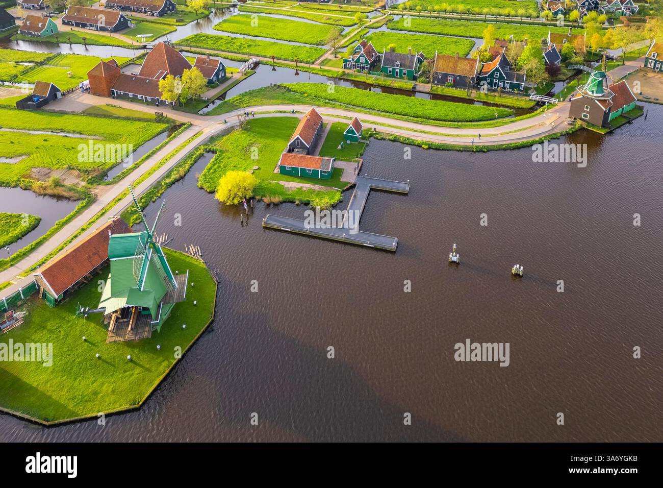 Luftaufnahme der typischen Windmühlen von Zaanse Schans auf dem Fluss Zaan im Frühling. Zaanse Schans, Nordholland, Gemeinde Zaanstad, Niederlande Stockfoto