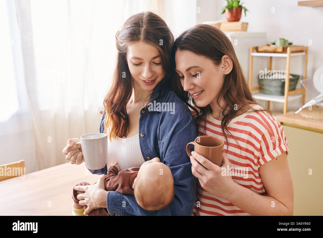 Zwei stolze Mütter umarmen ihr Kind am Muttertag und teilen einen warmen und intimen Moment miteinander. Stockfoto