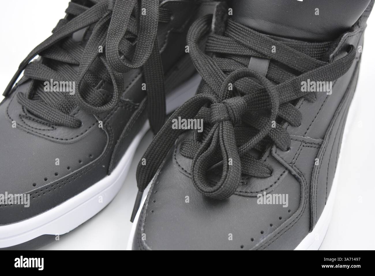 Schöne, junge Sportschuhe, schwarze Stiefel mit weißen harten Sohlen sind auf einem weißen plasti.. Warme Halbstiefel aus Leder mit Isolierung. Stockfoto