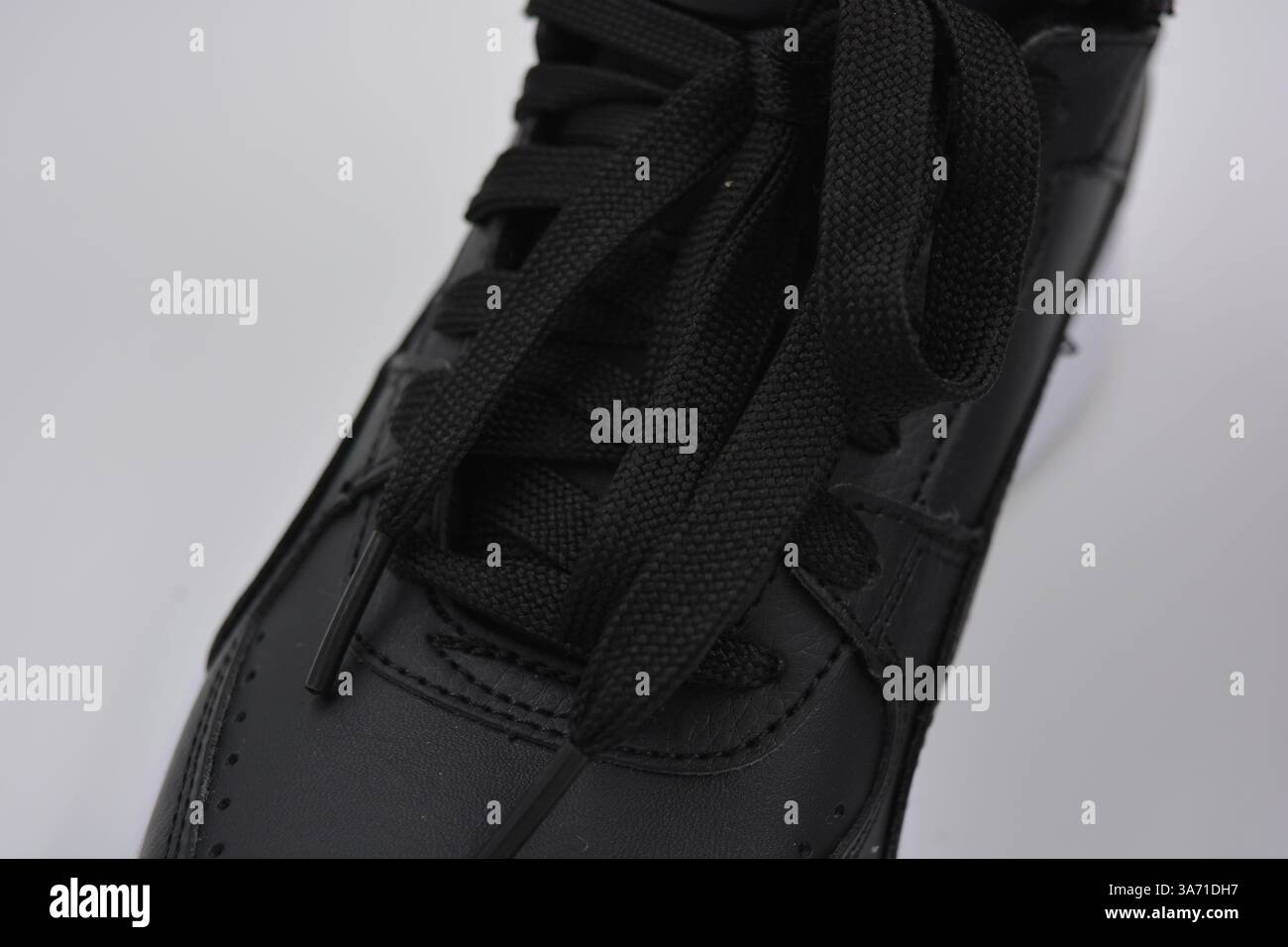 Schöne, junge Sportschuhe, schwarze Stiefel mit weißen harten Sohlen sind auf einem weißen plasti.. Warme Halbstiefel aus Leder mit Isolierung. Stockfoto