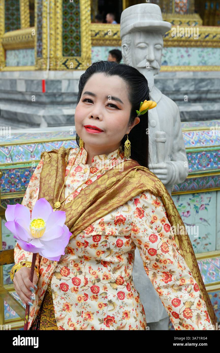 Elegante südasiatische Frau in traditioneller Kleidung hält eine Blume und fängt kulturelles Erbe, zeitlose Schönheit und anmutige Mode ein. Stockfoto