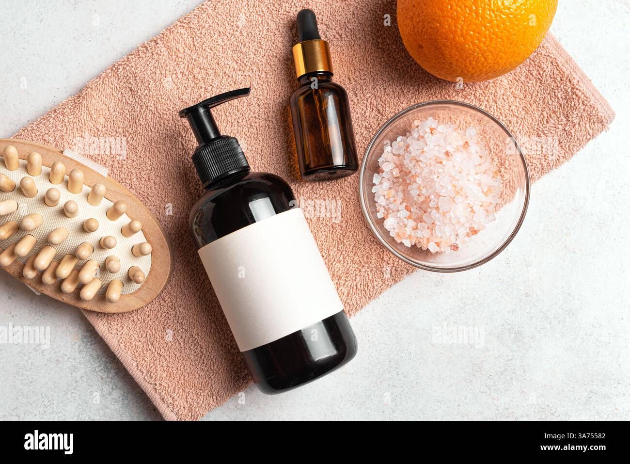Flasche und Tropfer für Kosmetikprodukte, Holzbürste für Anti-Cellulite-Massage und Orangenfrucht flach auf beigem Handtuch. Anti-Cellulite, Körper ca. Stockfoto