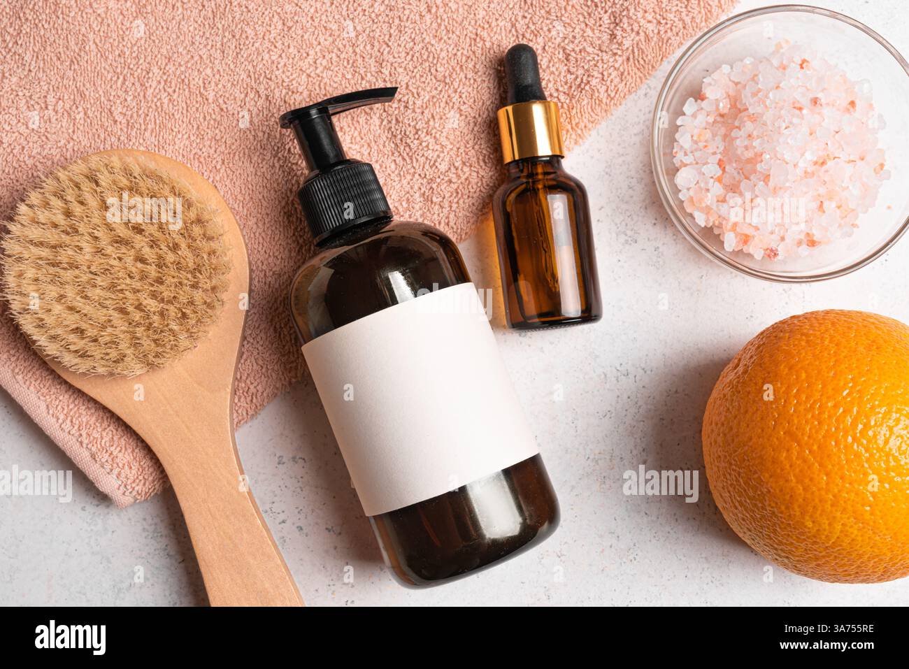 Flasche für Kosmetikprodukte, Holzbürste für Anti-Cellulite-Trockenmassage und Orangenfrucht flach auf Handtuch legen. Anti-Cellulite, Körperpflege, Entgiftung A Stockfoto