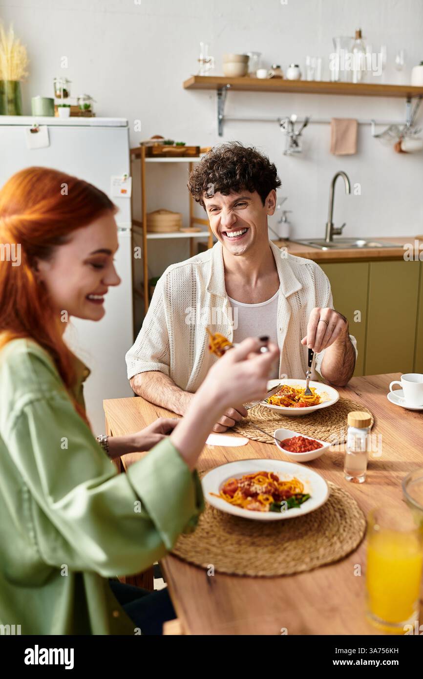 Zwei junge Liebhaber teilen sich Lachen und eine köstliche hausgemachte Mahlzeit zu Hause und schaffen freudige Erinnerungen. Stockfoto