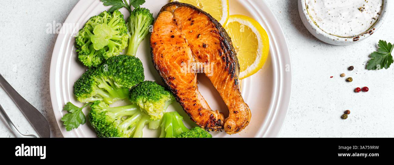 Gegrilltes Lachsfischsteak mit gedämpftem Gemüse und Joghurtsauce, Bannerformat. Gesunde Fitness-Lebensmittel, Keto Diät Mahlzeit Konzept. Stockfoto