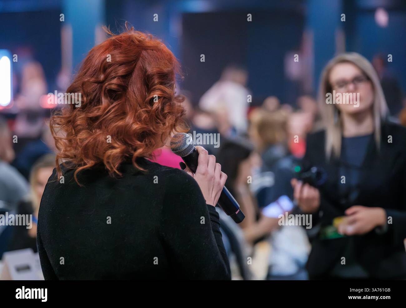 Referent, der dem Publikum auf einer Geschäftskonferenz präsentiert. Professionelle Vernetzung mit einem Mikrofon. Stockfoto