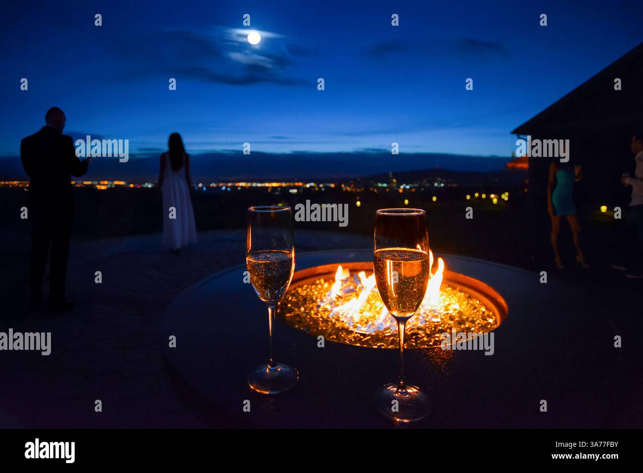 Eine abendliche Cocktailparty im Freien auf einer Terrasse mit Feuerstelle mit Blick auf das Tal und die Stadt Spokane, Washington USA. Stockfoto