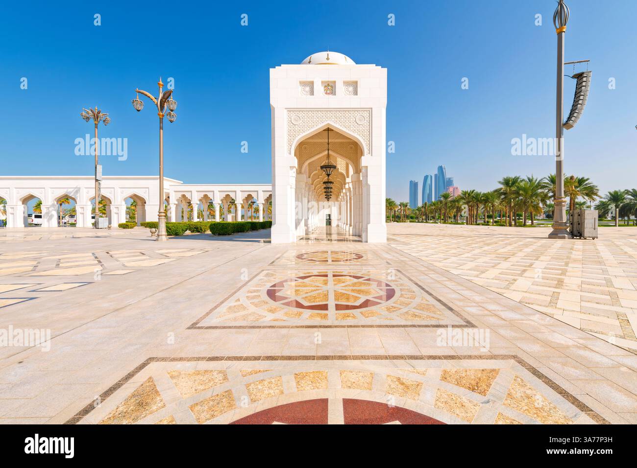 Ein weißer Marmorbogengang mit der modernen Skyline hinter dem Qasr Al Watan, dem königlichen Präsidentenpalast in Abu Dhabi, Vereinigte Arabische Emirate. Stockfoto