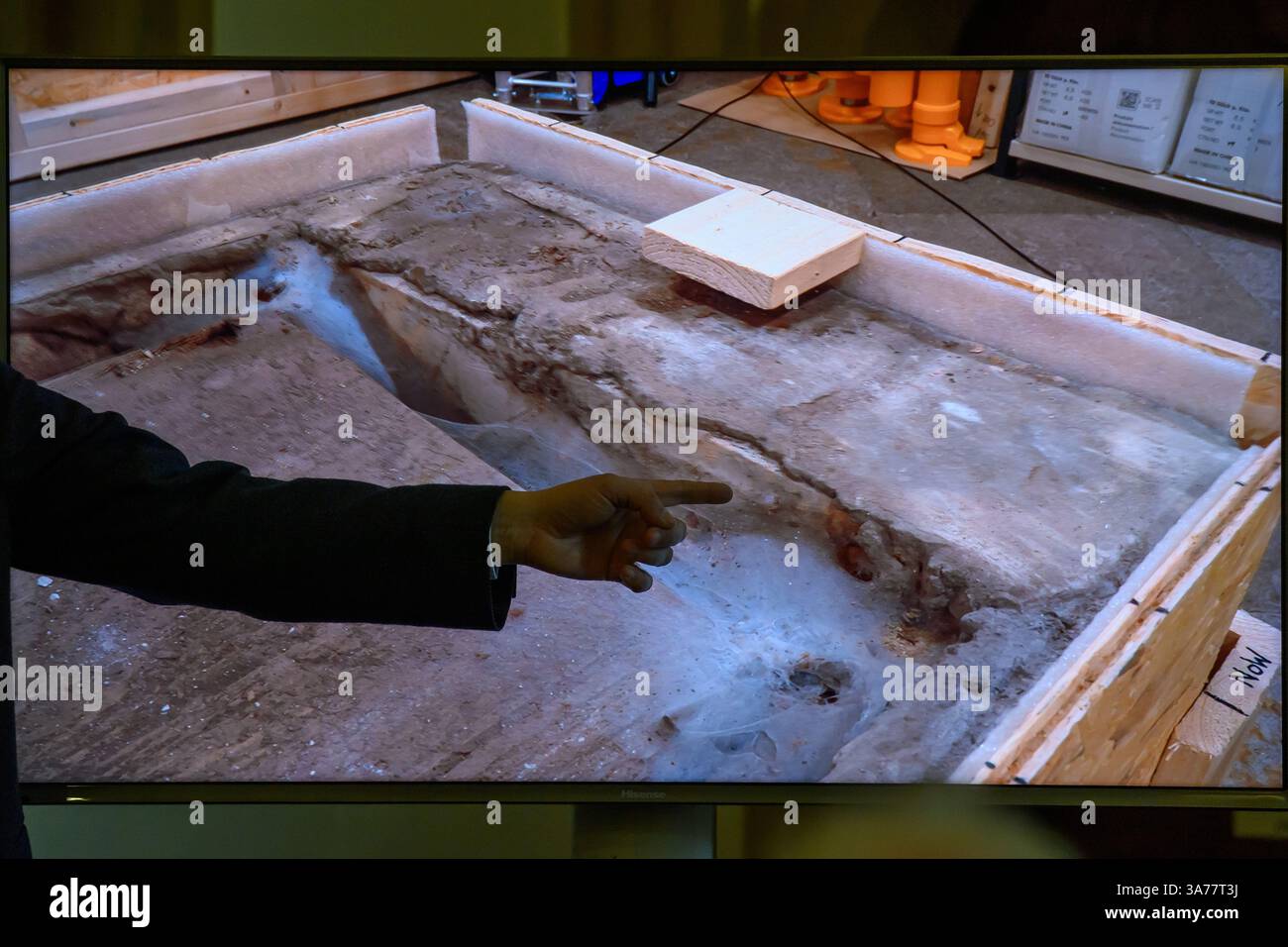 26. März 2025, Sachsen-Anhalt, Magdeburg: In der Sakristei des Magdeburger Doms erklärt Donat Wehner (l) vom Landesamt für Denkmalpflege und Archäologie Sachsen-Anhalt Medienvertretern die Beschädigung der Holzkiste im offenen Sarkophag mit Hilfe einer Live-Videoübertragung aus dem Gehege rund um das Grab Ottos des Großen. Seit Januar führen das Landesamt für Denkmalpflege und Archäologie und die Kulturstiftung Sachsen-Anhalt Untersuchungen zur Erhaltung des Denkmals durch. Die Ergebnisse der Untersuchungen bis Stockfoto