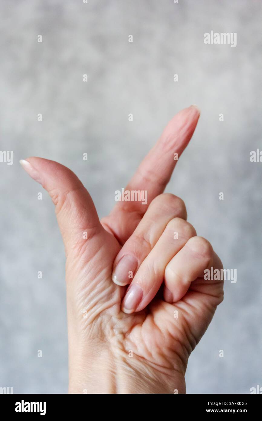 Die Hand einer Frau berührt oder zeigt auf einen isolierten grauen Hintergrund. Stockfoto