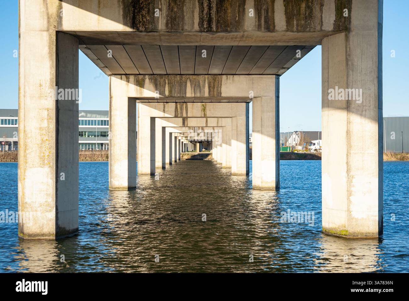 Perspektivischer Effekt mit sich wiederholenden Säulen einer großen Eisenbahnbrücke über Wasser, perspektivischer Effekt. Stockfoto