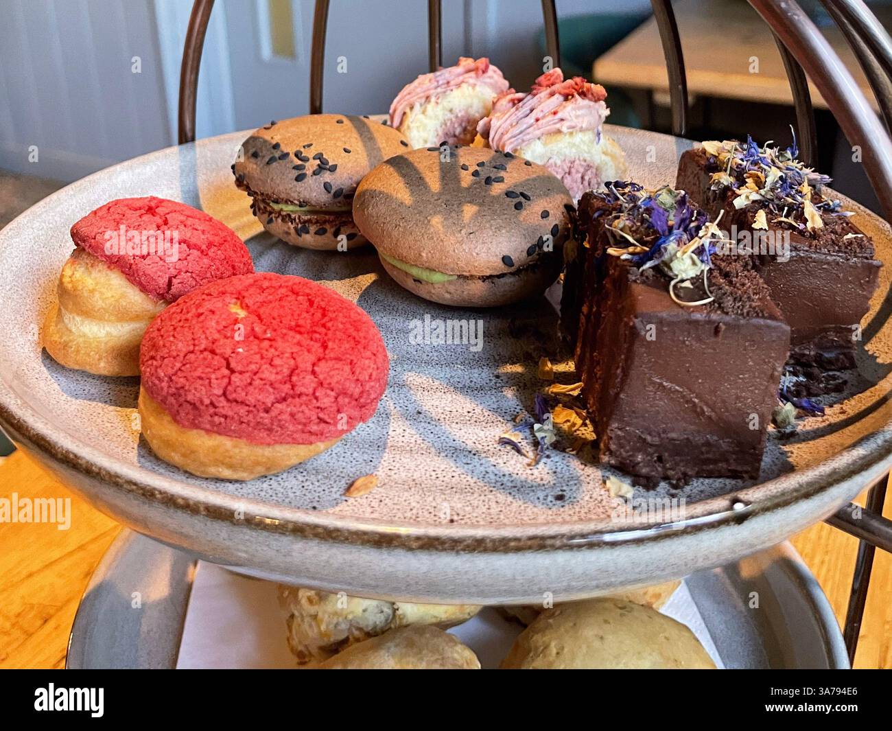 Mehrstufiger Nachmittagstee mit süßen und herzhaften Köstlichkeiten in einem gemütlichen Café. Stockfoto