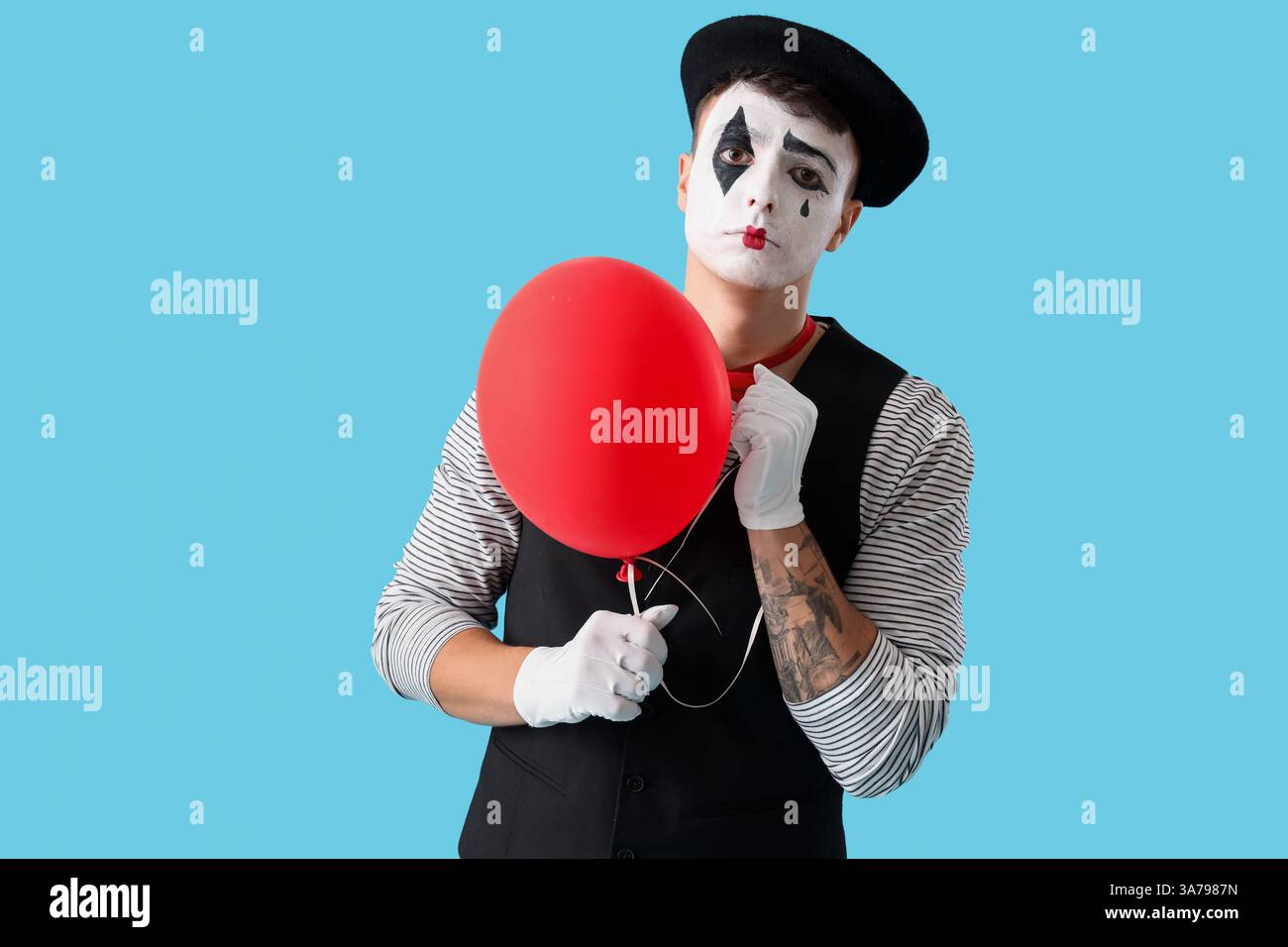Männlicher Pantomimist mit Ballon auf blauem Hintergrund Stockfoto