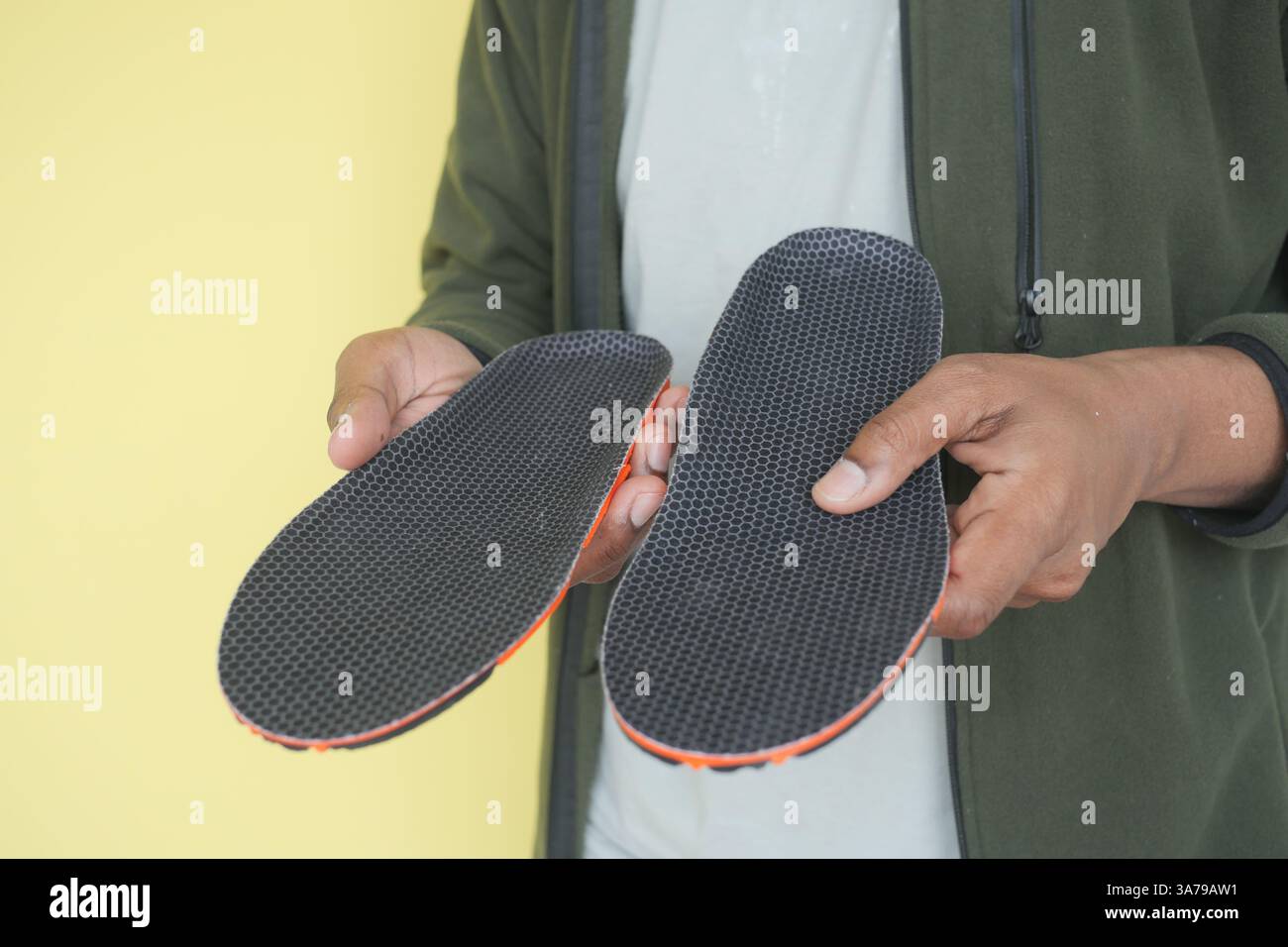 Einzigartige Einlegesohlen, die lässig vor gelbem Hintergrund gehalten werden Stockfoto