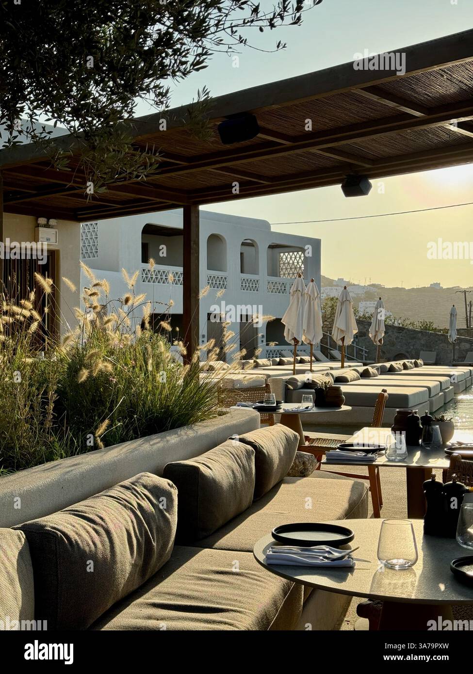 Ein Blick am frühen Morgen auf das Restaurant und die Poolbereiche des Hotels Domes Noruz Mykonos an einem sonnigen Tag. - Smartphone-aufgenommenes Stockfoto