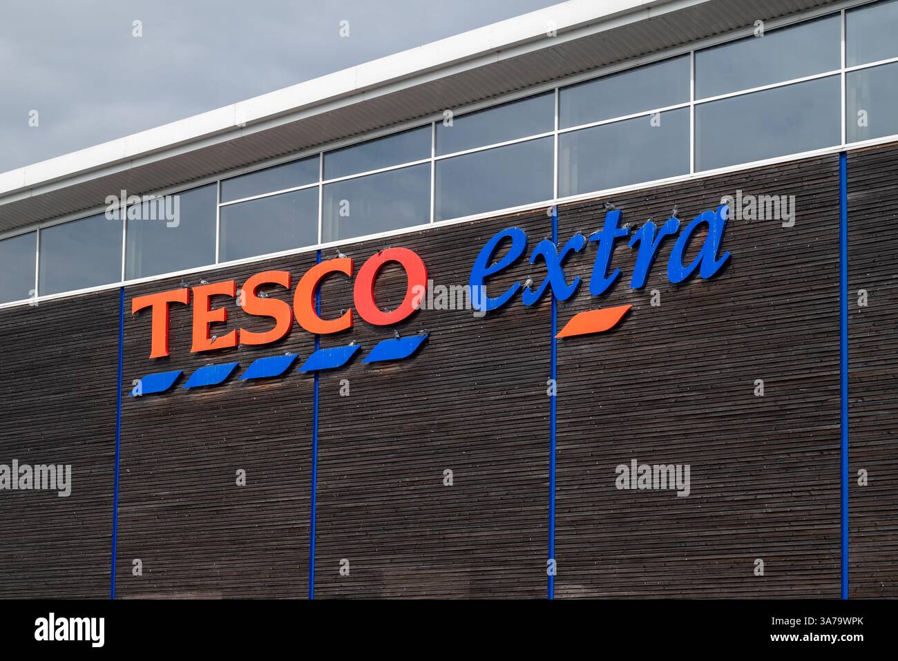 Rot-blaues Tesco extra Schild an der Seite eines modernen Gebäudes. März 2025. Stockfoto