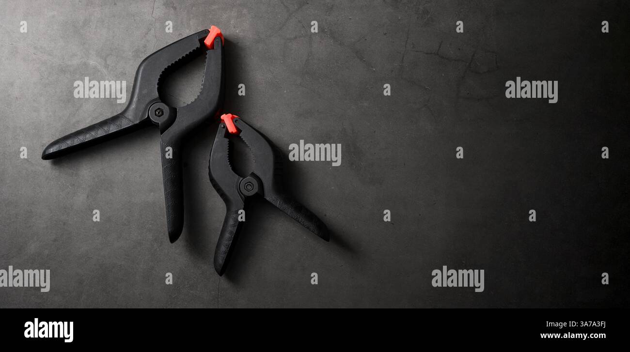 Orangefarbene schwarze Kunststoffklemme auf dunkelgrauem Steinhintergrund Stockfoto