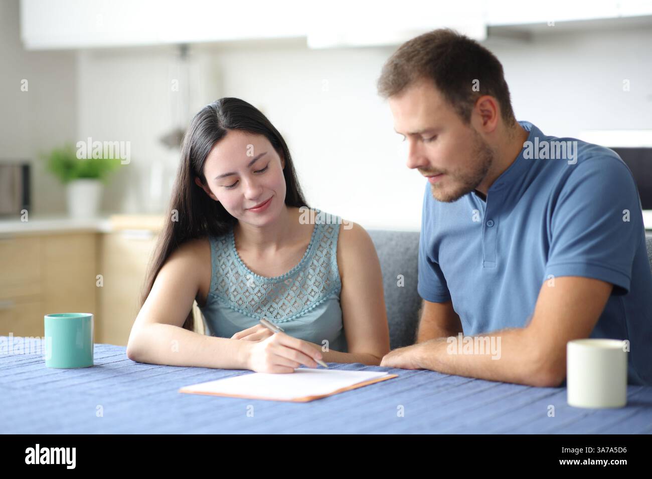 Interrassische Mitbewohner unterzeichnen einen Papiervertrag in der Küche zu Hause Stockfoto
