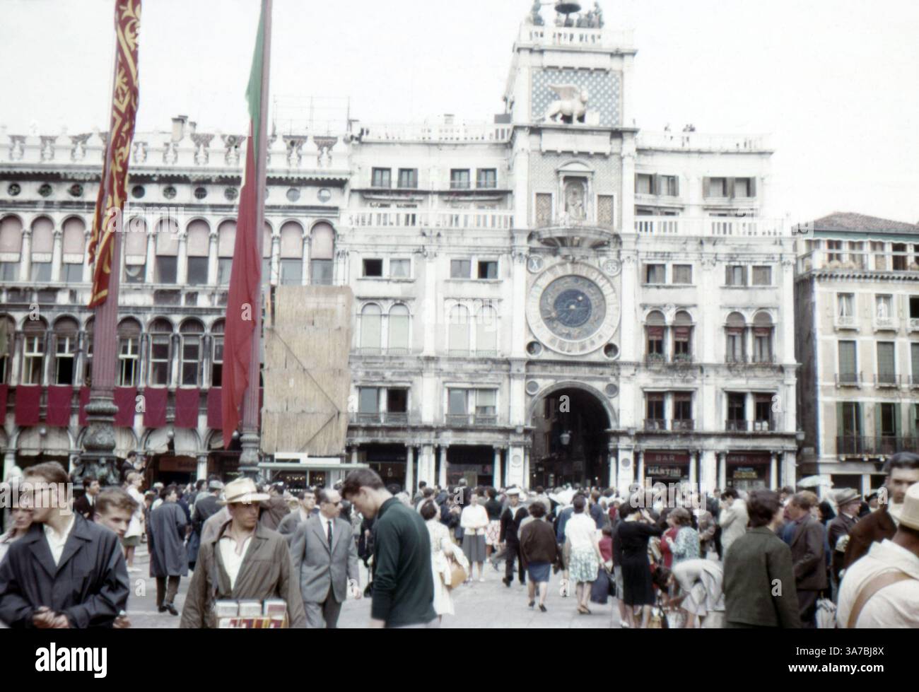 Der Uhrenturm in Venedig ist ein Gebäude der frühen Renaissance an der Nordseite des Markusplatzes, am Eingang zur Merceria. Es besteht aus einem Turm, in dem sich die Uhr befindet, und unteren Gebäuden auf jeder Seite. Er grenzt an das östliche Ende der Procuratie Vecchie. Aufgenommen im Juli 1965 auf 35-mm-Diafilm. Stockfoto