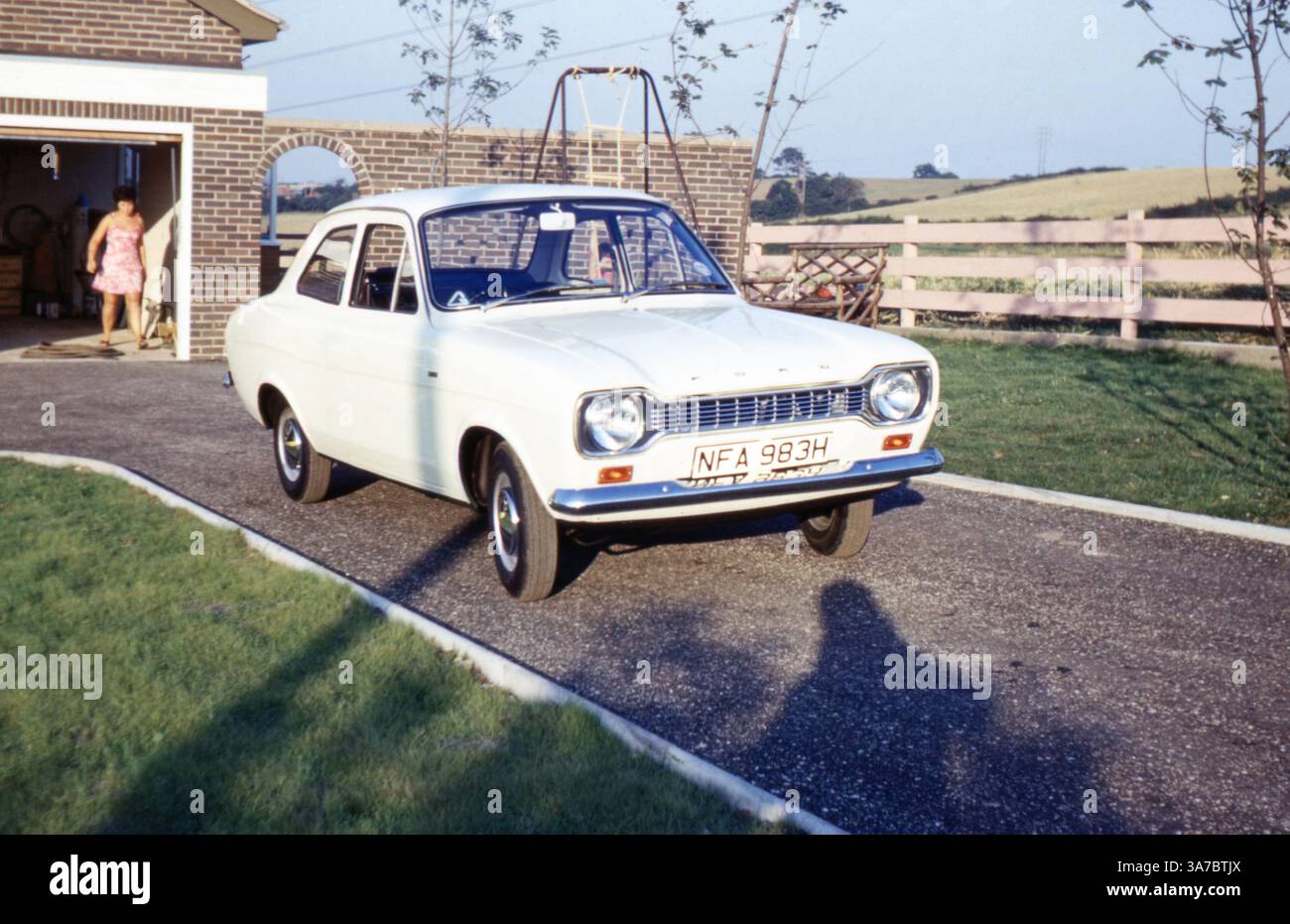 Ein unberührter weißer Ford Escort Mk1 mit Kennzeichen NFA 983H (1969–1970) parkt ordentlich auf einer Einfahrt neben einer Backsteingarage auf dem britischen Land, etwa Ende der 1960er oder Anfang der 1970er Jahre Stockfoto
