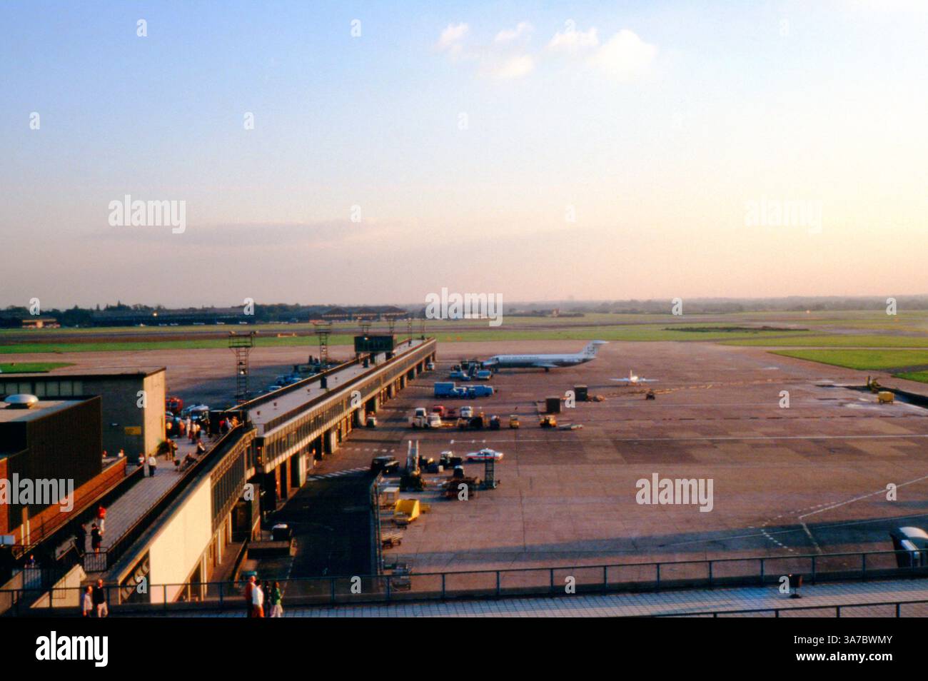 Ein Blick auf den Flughafen Manchester in den 1970er Jahren, mit Blick auf das Hauptfeld des Terminals mit geparkten und angeflogenen Flugzeugen aus der Zeit. Die Passagiere können auf der Aussichtsplattform im Freien, einem der häufigsten Merkmale des Flughafens der Zeit, beobachtet werden. Stockfoto