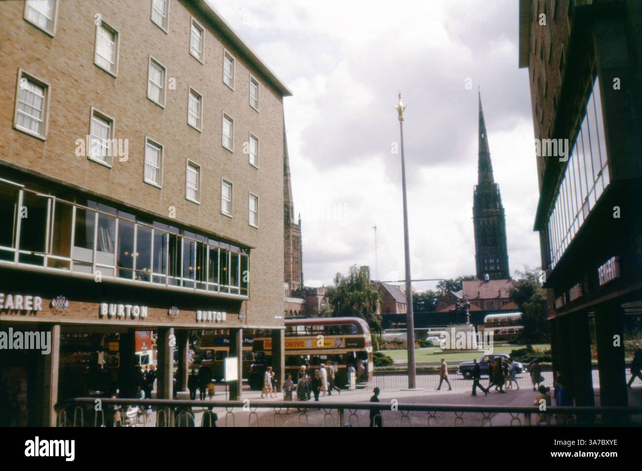 Eine lebendige Straßenszene aus den 1960er Jahren in Broadgate, Coventry, aufgenommen auf 35-mm-Diafilmen. Die Lady Godiva Statue steht stolz im Stadtzentrum, während die Leute an Geschäften wie Burton und C&A vorbeilaufen Doppeldeckerbusse und Architektur aus der Mitte des Jahrhunderts bilden die Kulisse, in der Ferne erhebt sich der Turm der Kathedrale von Coventry. Stockfoto