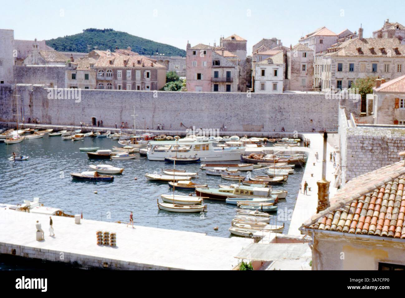 Eine lebhafte Sommerszene am Alten Hafen von Dubrovnik mit zahlreichen kleinen Booten, die neben den historischen Stadtmauern und mittelalterlichen Gebäuden liegen, die im August 1967 in Kroatien (damals Jugoslawien) erfasst wurden. Stockfoto