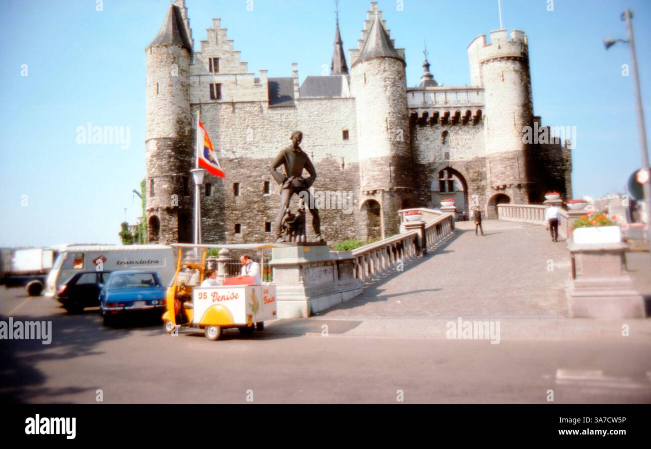Het Steen, eine mittelalterliche Festung in Antwerpen, Belgien, die ursprünglich im frühen Mittelalter erbaut und um 1530 wieder aufgebaut wurde. Sie steht am Rande der Schelde, mit ihren Steintürmen und der Eingangsbrücke gut sichtbar. Davor befindet sich die Statue von lange Wapper, einem flämischen Folklore-Riesen. Ein Vintage-Eiswagen und geparkte Fahrzeuge verleihen der Szene ein nostalgisches Gefühl der 1970er Jahre. Stockfoto