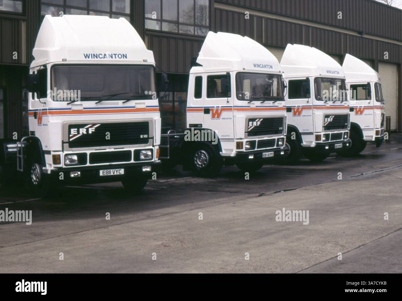 Aufgenommen im Jahr 1988 mit einer Reihe von ERF E10-Lkw, die von Wincanton, einem bekannten britischen Logistikunternehmen, betrieben werden. Die LKW stehen ordentlich vor einem Verteilerlager, und die Wagen mit den Namen „Gigant“ und „Halifax“ sind in den Fahrerhäusern zu sehen. Diese in Wincantons markanter weiß-oranger Lackierung lackierten ERF-Lkw repräsentieren eine klassische Ära in der britischen Güterkraftverkehrsgeschichte. Stockfoto