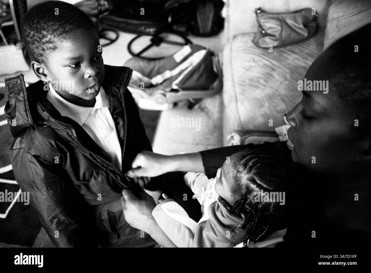 13. Oktober 2012 - Syracuse, NY, USA - Benithia zieht die Jacke ihres Sohnes Iden an, bevor sie nach draußen gehen. Benithia kommt aus Florida und ist besorgt darüber, dass sie das Geld hat, um die richtige Winterkleidung für ihre Kinder in Syrakus zu kaufen. 2012 floh Benithia Ganious aus einer missbräuchlichen Beziehung und brachte zwei ihrer drei Kinder von Port Saint Lucie, Florida nach Syracuse, New York. (Kreditbild: © Andrew Renneisen/ZUMAPRESS.com) Stockfoto