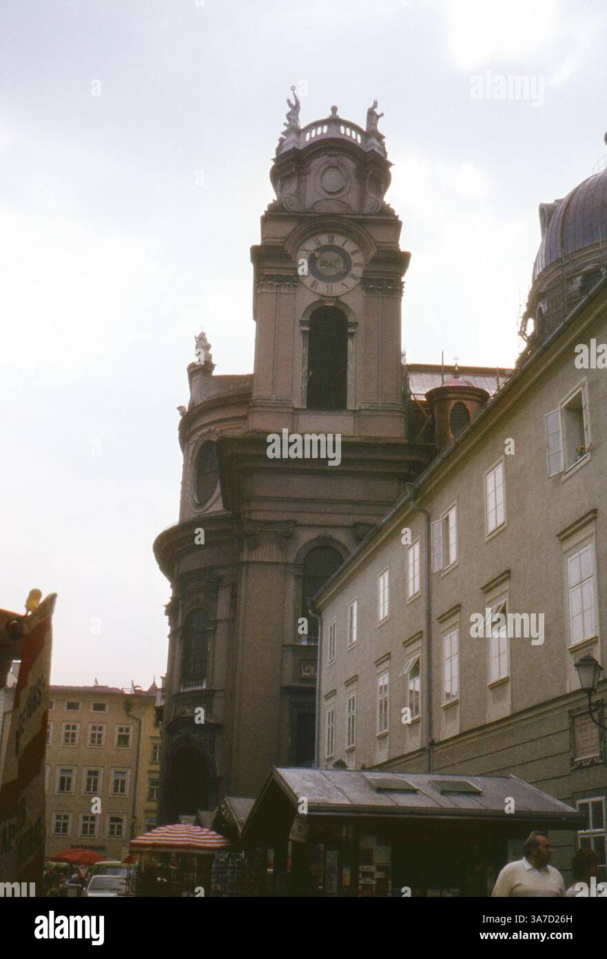 Der barocke Glockenturm der Kollegienkirche erhebt sich über der Altstadt von Salzburg, Österreich, von einem nahe gelegenen Platz mit lokaler Aktivität. Die architektonischen Details und die Kuppelstruktur heben die Pracht der Kirche aus dem 18. Jahrhundert hervor, ein Wahrzeichen des historischen Zentrums und ein Symbol für Salzburgs religiöses und kulturelles Erbe. Stockfoto Der barocke Glockenturm der Kollegienkirche erhebt sich über der Altstadt von Salzburg, Österreich, von einem nahe gelegenen Platz mit lokaler Aktivität. Die architektonischen Details und die Kuppelstruktur heben die Pracht der Kirche aus dem 18. Jahrhundert hervor, ein Wahrzeichen des historischen Zentrums und ein Symbol für Salzburgs religiöses und kulturelles Erbe. Stockfoto