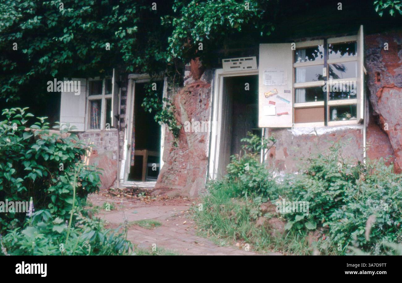Efeu und Grün umrahmen die Eingänge zu den Holy Austin Rock Houses in Kinver, ein erhaltenes Beispiel für Englands seltene Tradition von Sandsteinklippenhäusern, reich an ländlicher Geschichte. Fotografiert in den frühen 1990ern Stockfoto