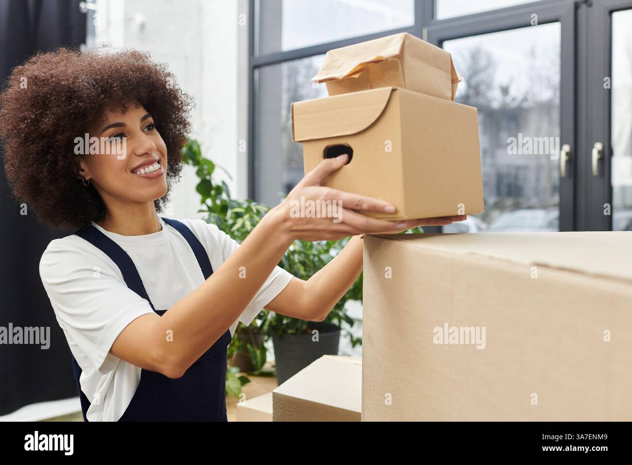 Eine Frau arrangiert aktiv ihre Kisten und bringt mit Freude Ordnung in ihre neue moderne Wohnung. Stockfoto