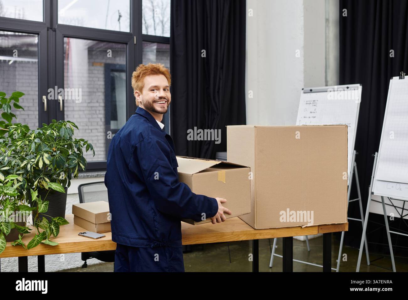 Man arrangiert verpackte Kartons in einer modernen Büroumgebung während eines vielbeschäftigten Umsiedlungsprozesses. Stockfoto