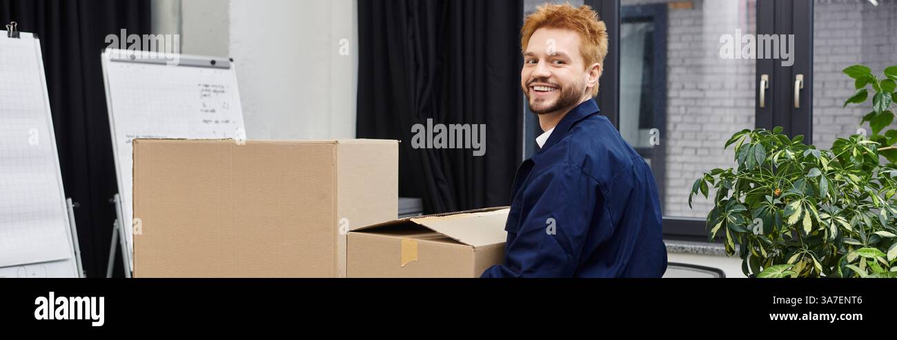 Ein fröhlicher Mann packt Kisten und bereitet sich auf einen Umzug in einer modernen Büroumgebung vor. Stockfoto