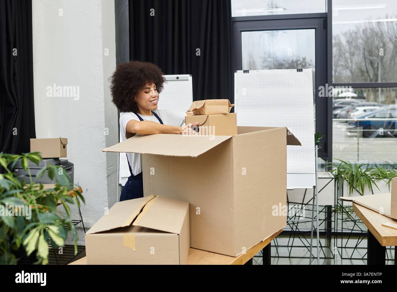 Eine engagierte Frau ist damit beschäftigt, Gegenstände in Kisten in einem modernen Büro zu packen. Stockfoto