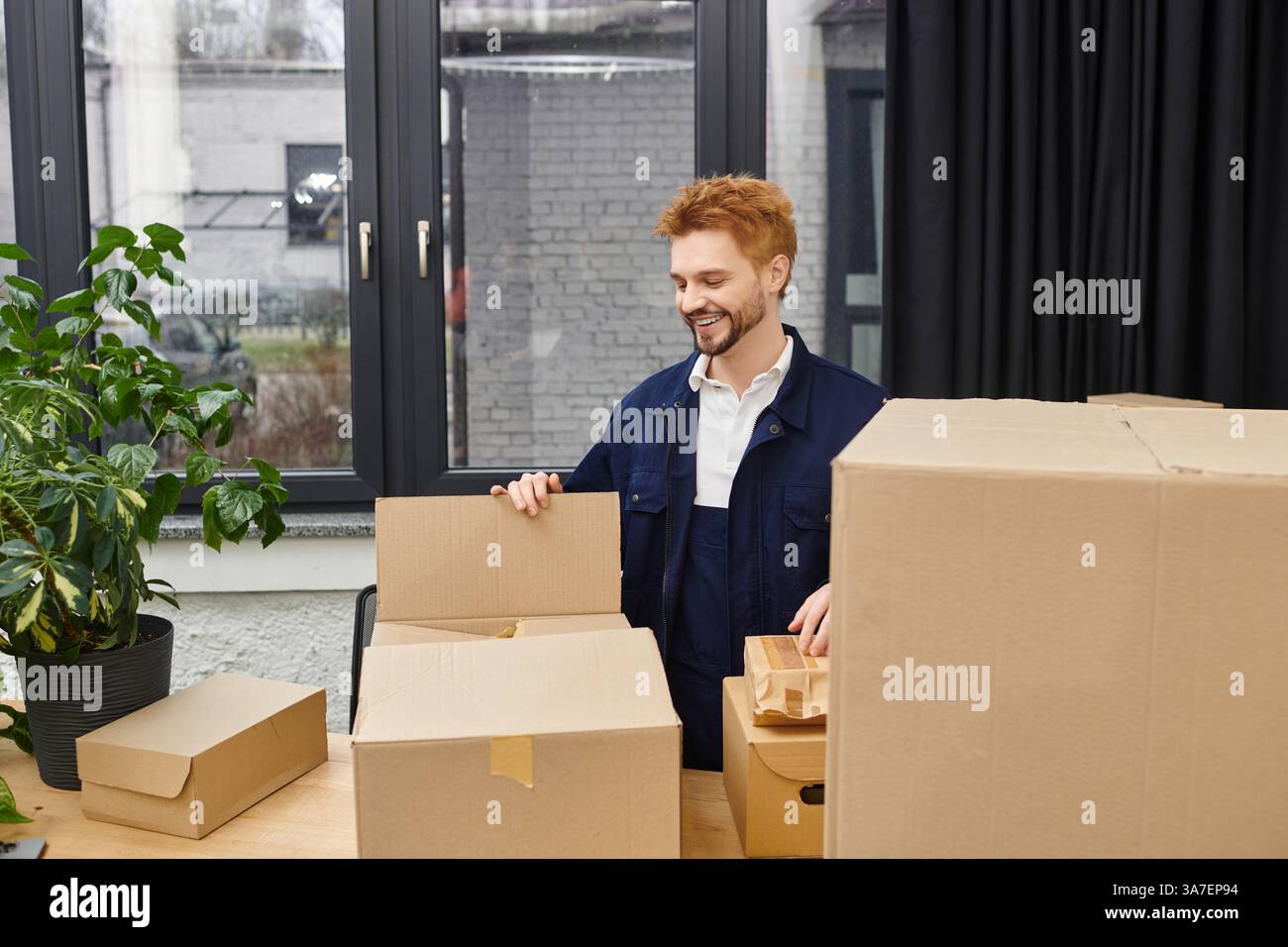 In einem modernen Büro durchsucht ein Mann gerne Kisten und macht sich bereit zum Auspacken. Stockfoto