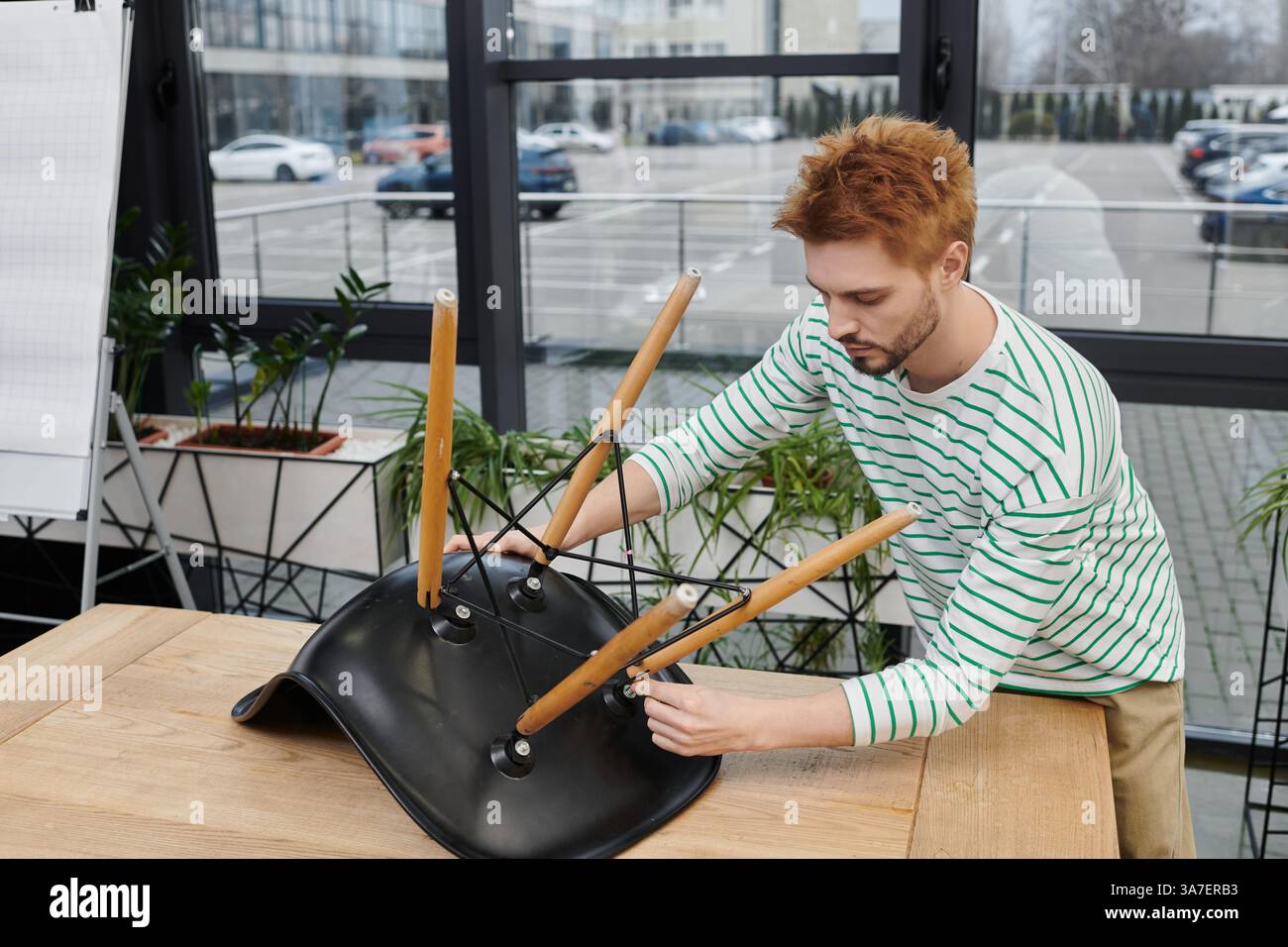 Man konzentriert sich darauf, während des Umzugs Möbel in einem hellen, offenen Bereich zusammenzustellen. Stockfoto