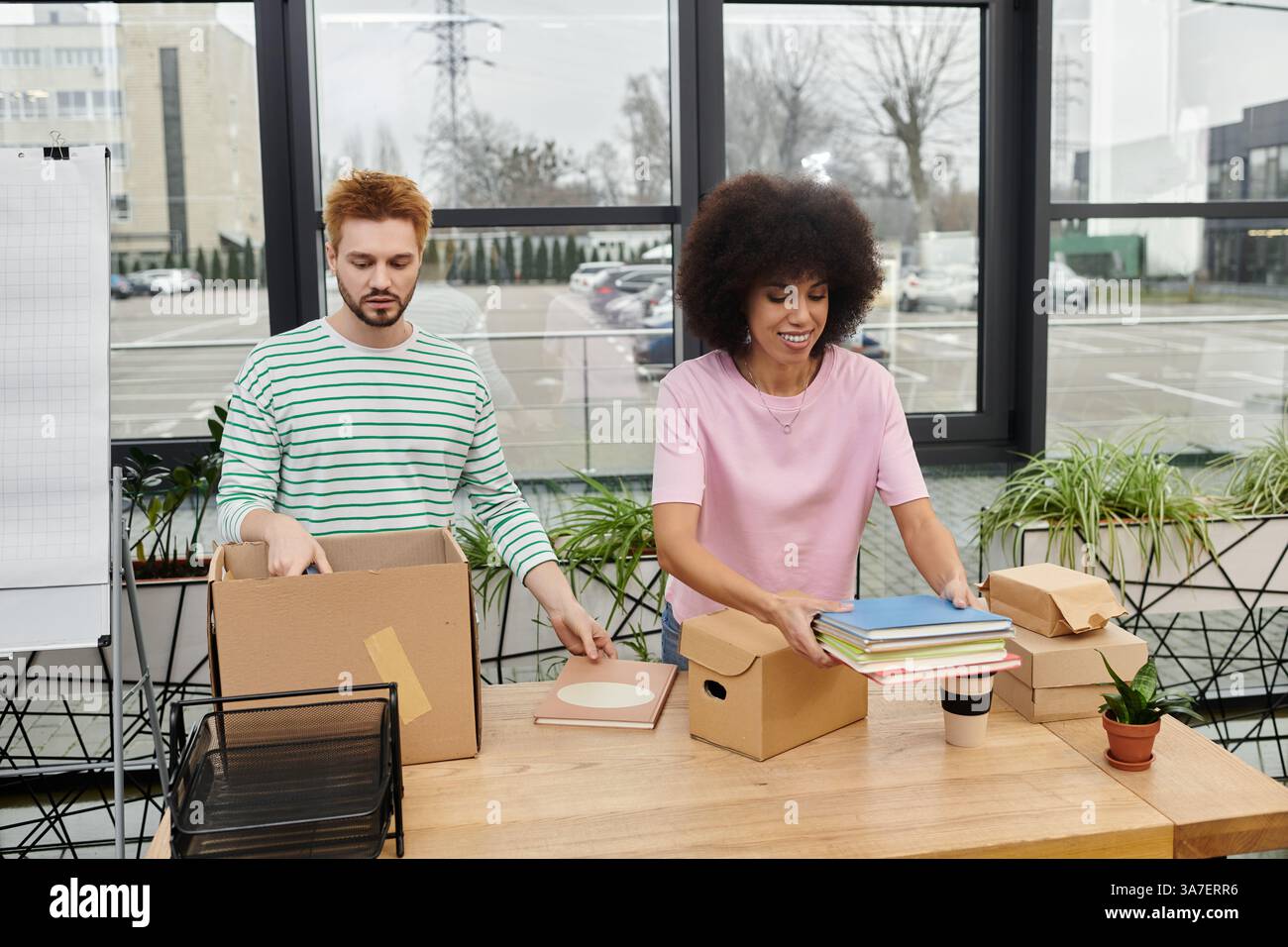 Zwei Personen organisieren zusammen Kartons mit Büromaterial während eines Umzugs. Stockfoto