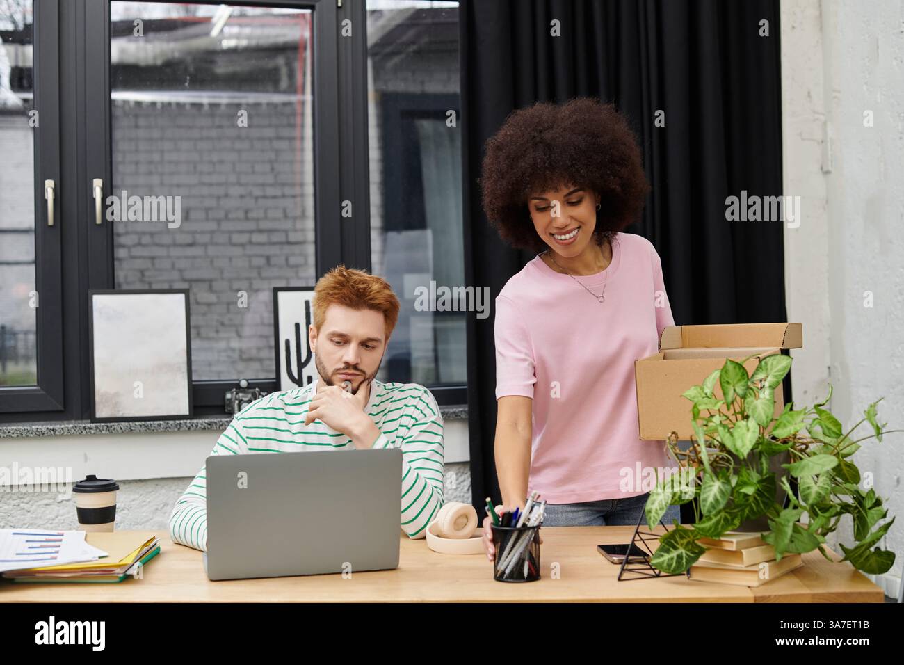 Ein Mann und eine Frau nehmen an der Verpackung und dem Auspacken Teil, während sie auf einen neuen Arbeitsplatz umsteigen. Stockfoto