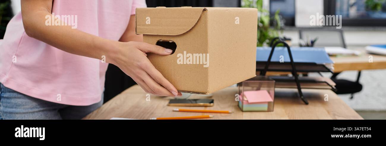 Frau verpackt Gegenstände sorgfältig in einen Karton während eines modernen Umzugs Stockfoto