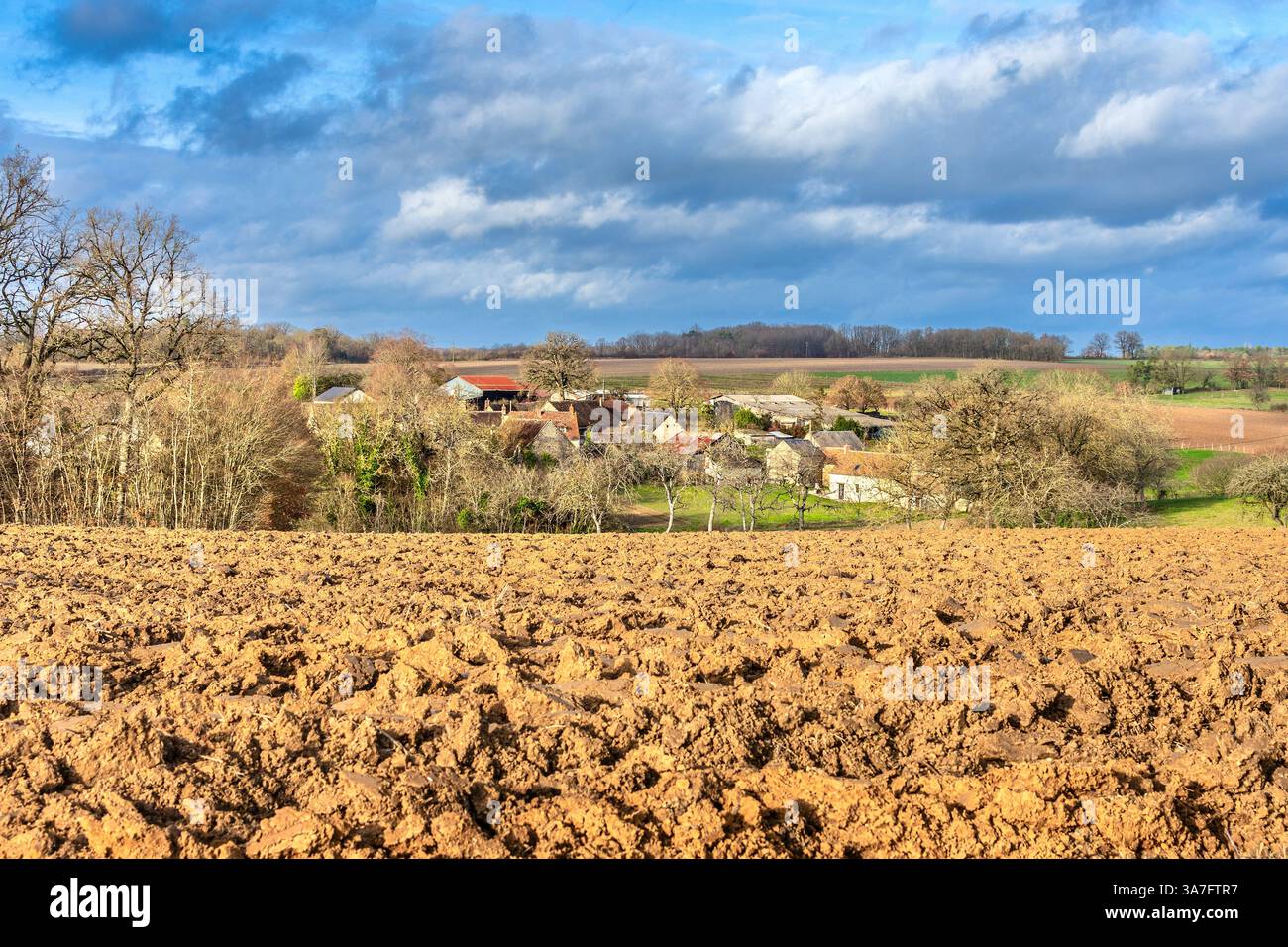 Sud-Touraine-Landschaft mit neu gepflügtem Feld und dem Weiler La Buttiere in der Ferne - Bossay-sur-Claise, Indre-et-Loire (37), Frankreich. Stockfoto