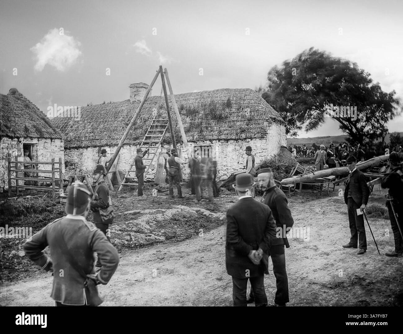 Eine Vintage-Fotografie einer Räumungsszene in County Clare Mitte des 19. Jahrhunderts. Mit der Einrichtung eines Rammbocks. Die Mieter wurden hauptsächlich von anglo-irischen Vermietern vertrieben, als sie in schwere Zeiten gerieten, oft als Folge der großen irischen Hungersnot. Die meisten Vertreibungen erfolgten in den 1840er Jahren, als die Polizei begann, eine Zählung zu führen. Insgesamt wurden zwischen 1849 und 1854 fast 250.000 Personen offiziell vertrieben. Die Räumungen dauerten bis in die 1890er Jahre an Stockfoto