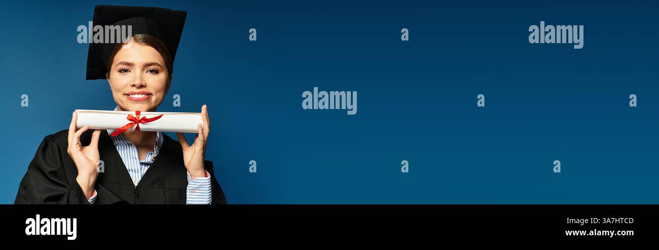 Eine junge Frau in Abschlussbekleidung strahlt vor Stolz und hält ihr Diplom. Stockfoto